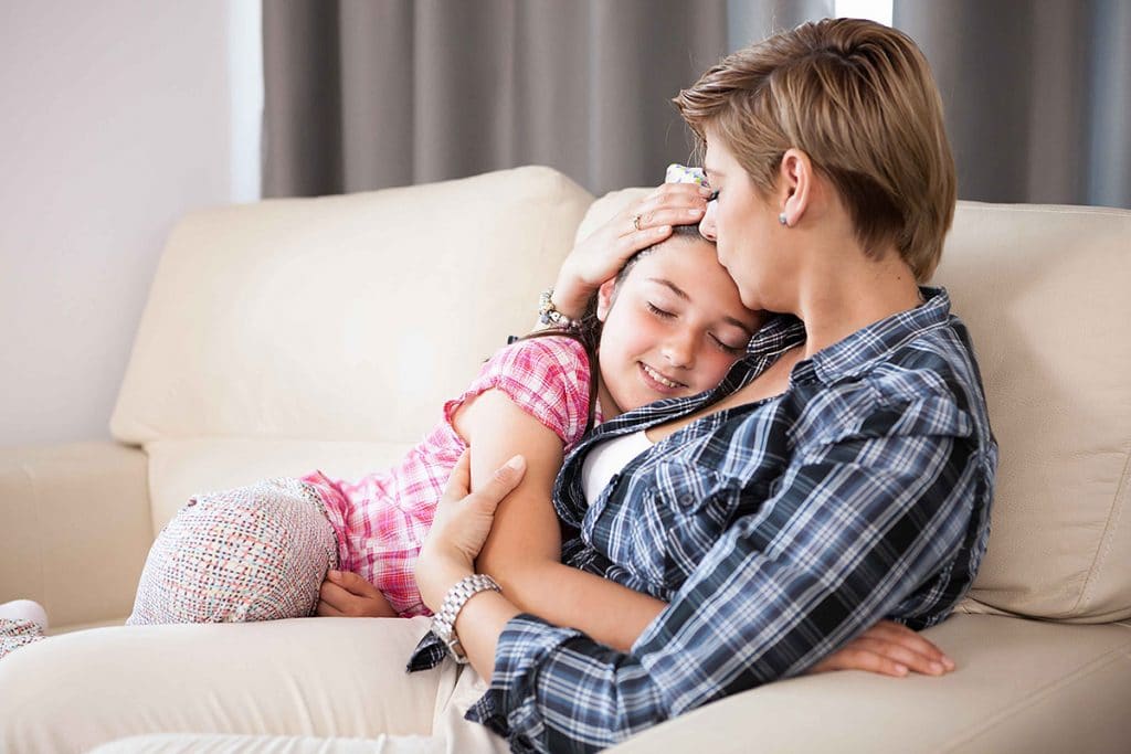 Mother kisses her daughter on the forehead