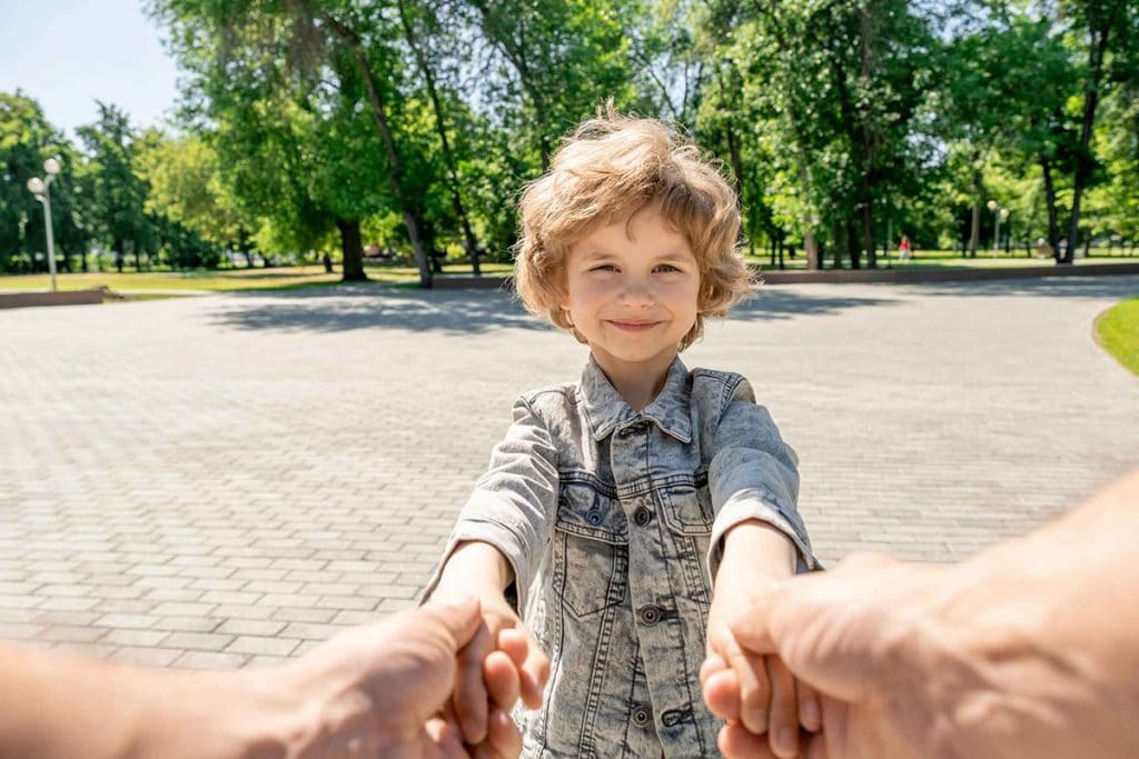 Happy little boy with blond curly hair looking at his parent whi